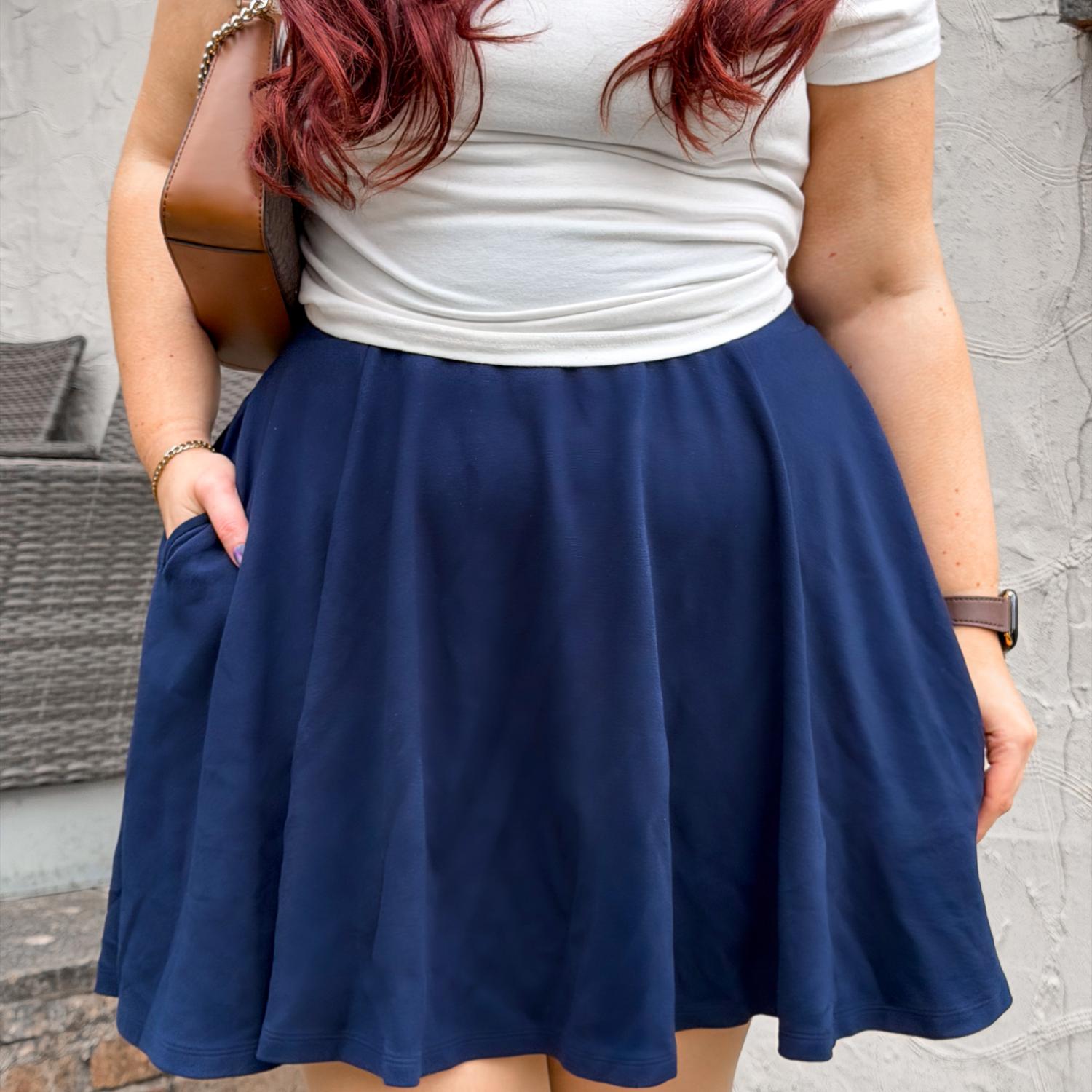 Person wearing a blue skirt and white top with a neutral background
